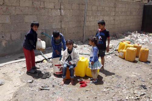 Yemeni people fill plastic barrels with clean water, distributed by charities, in Madhbah village of Sana'a, Yemen [Mohammed Hamoud - Anadolu Agency]