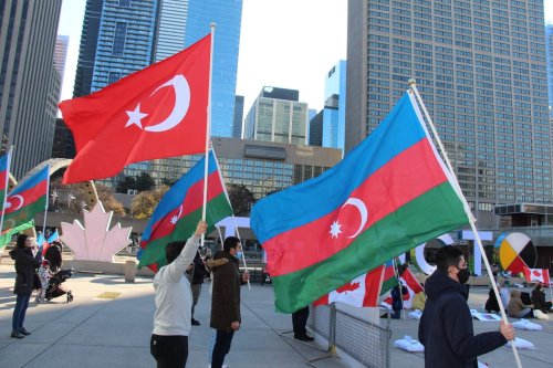 TORONTO, CANADA - NOVEMBER 14: A group of Azerbaijani people wave Azerbaijani and Turkish flags as they stage a protest by laying 93 pillows and red carnations with the names of 93 Azerbaijani civilians who killed during Armenian attacks, in front of the Toronto City Hall, Toronto, Canada on November 14, 2020. ( Seyit Aydoğan - Anadolu Agency )
