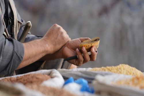 A seller holds money at a market area in Taiz, Yemen on March 10, 2022 [Abdulnasser Alseddik/Anadolu Agency]