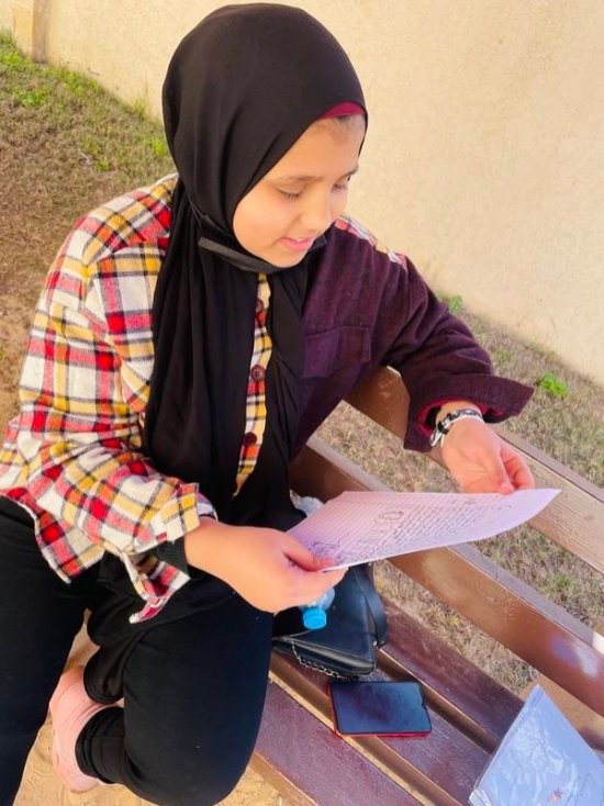 Child in Gaza reading a pen pal letter