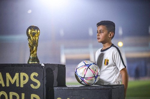 A view as a child stands next to a World Cup replica football on November 19, 2022 [Muhammed Said/Anadolu Agency]