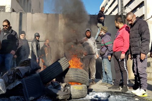 Municipal workers set tires on fire at the entrance of central bank of Lebanon to protest restrictions on withdrawal of US dollar with official exchange rate in Tripoli, Lebanon on February 20, 2023 [Ahmed Said - Anadolu Agency]
