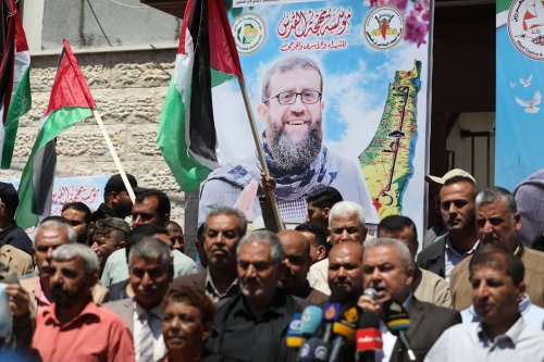 People gather to demonstrate in front of the International Committee of the Red Cross (ICRC) building in Gaza City, Gaza while they hold the poster of Palestinian prisoner Khader Adnan who died after an 87 day hunger strike at an Israeli prison, on May 02, 2023 [Mustafa Hassona/Anadolu Agency]
