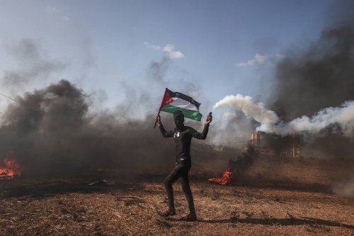 Gazaian people holding the Palestine flag set tyre on fire to stage a protest against killing Palestinians by Israeli forces, in Gaza Strip on June 19, 2023 [Ali Jadallah/Anadolu Agency]