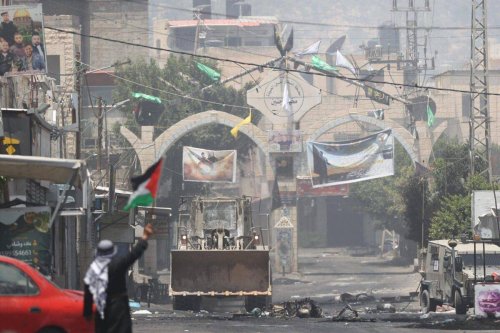 A Palestinian man holds Palestinian flag as he protest Israeli forces continuing to conduct airstrike and raid on the second day in Jenin, West Bank on July 04, 2023 [Issam Rimawi - Anadolu Agency]