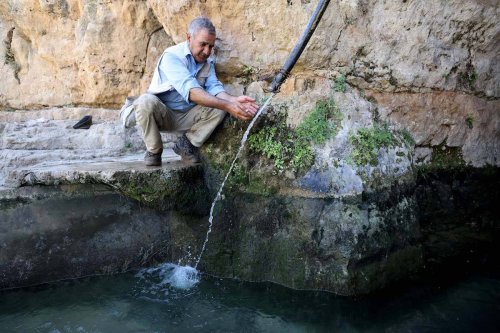 A man sits near Ayn Al-Hawiyah spring, one of the water springs in the historical Husan district in Jerusalem on July 18, 2023 [Issam Rimawi - Anadolu Agency]