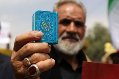 A man holds Quran as people gather after Friday prayers to protest against the act of Quran burning, in Tehran, Iran on July 21, 2023. [Fatemeh Bahrami - Anadolu Agency ]