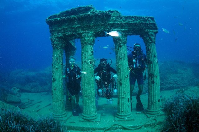 Divers pose for a photo with an underwater statue at the Side Underwater Museum, Turkiye's first underwater museum, in Manavgat district of Antalya, Turkiye on June 19, 2023. [Tahsin Ceylan - Anadolu Agency]