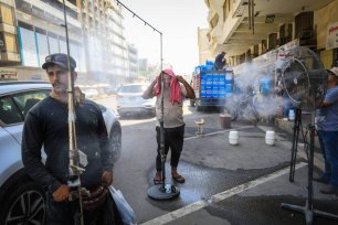 Iraqis are trying to cool off with "water-spraying fans" placed on the roadside on summer days when the air temperature reaches 50 degrees in the capital, Baghdad, where high temperatures are effective, on August 01, 2023 [Murtadha alsudani/Anadolu Agency]
