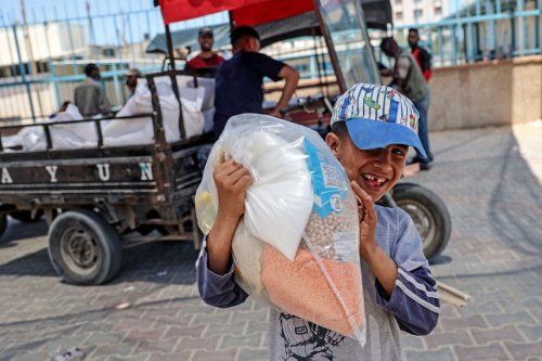 A Palestinian boy carries a bag of food aid in Gaza Strip on 26 May 2021 [SAID KHATIB/AFP/Getty Images]