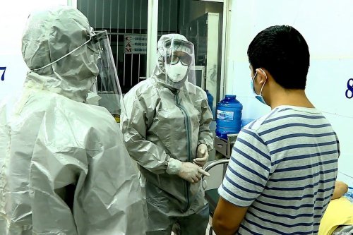 Medical personnel wearing protectice suits interact with two patients (R on bed and standing) tested positive to the coronavirus in an isolation room at Cho Ray hospital in Ho Chi Minh City on January 23, 2020 [STR/Vietnam News Agency/AFP via Getty Images]