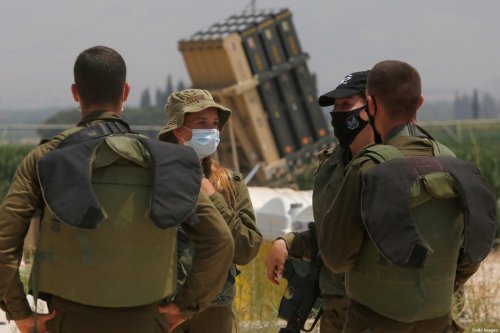 Israeli soldiers stand in front of an Iron Dome defence system battery in northern Israel near the border with Lebanon on 27 July 2020 [JALAA MAREY/AFP/Getty Images]
