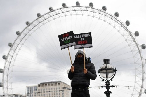 A pro-Palestine activist holds a placards opposite the London Eye as they march in central London on 22 May 2021. [JUSTIN TALLIS/AFP via Getty Images]