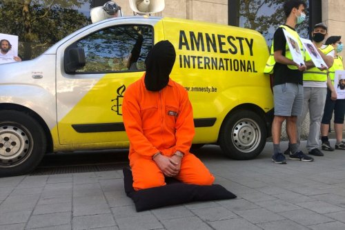 An Amnesty International member kneels on the ground during a protest to ask the closure of the Guantanamo Bay prison, at the US embassy in Brussels on June 14, 2021 [NILS QUINTELIER/BELGA/AFP via Getty Images]