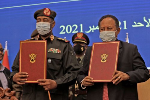 Sudan's top general Abdel Fattah al-Burhan (L) and Prime Minister Abdalla Hamdok lift documents during a deal-signing ceremony to restore the transition to civilian rule in the country in the capital Khartoum, on November 21, 2021 [AFP via Getty Images]