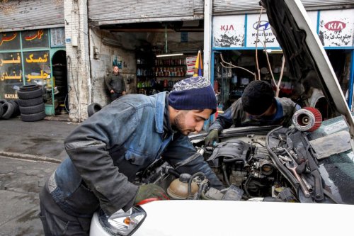 Mechanics repair a vehicle on February 20, 2022 [AFP via Getty Images]