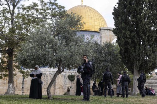 Israeli policemen stand guard before Muslim women praying by the Dome of the Rock (background) at the Aqsa mosques compound in the old city of Jerusalem on April 20, 2022 [MENAHEM KAHANA/AFP via Getty Images]
