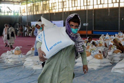 An Afghan man carries sacks of grains he received at a World Food Programme (WFP) facility as an aid to Afghan people with children suffering from malnourishment in Kandahar on April 21, 2022 [JAVED TANVEER/AFP via Getty Images]