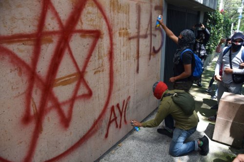 Students from Ayotzinapa paint slogans on the walls of the Israeli embassy in Mexico City during a demonstration on September 21, 2022, to demand the extradition of former General Attorney Tomas Zeron de Lucio. [CLAUDIO CRUZ/AFP via Getty Images]