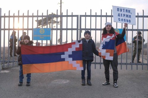 This photograph, taken on December 27, 2022, shows Armenian protestors standing in front of a Russian peacekeepers' checkpoint outside Stepanakert with a poster reading 'Putin! Keep Your Word' [ANI BALAYAN/AFP via Getty Images]