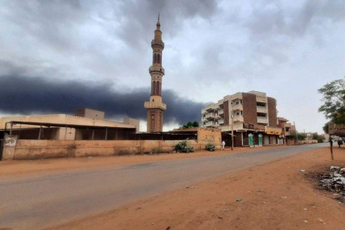 Smoke rises above buildings behind a nearly deserted street in Khartoum, on June 10, 2023 [AFP via Getty Images]