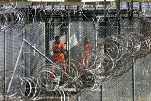 Dressed in bright orange coveralls, al-Qaida and Taliban prisoners wash before midday prayers at Camp X-Ray, where they are being held, at the US Naval Base at Guantanamo Bay, Cuba. [Photo credit should read J. SCOTT APPLEWHITE/AFP via Getty Images]