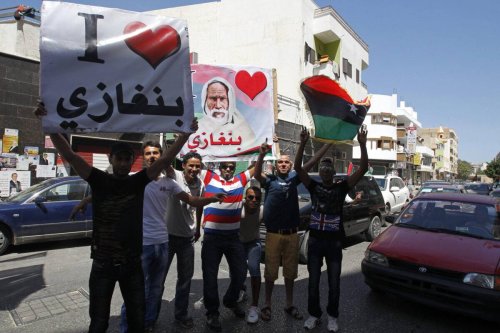 Libyan youth hold a picture of Libya's anti-colonialist resistance hero Omar al-Mukhtar and posters reading "I love Benghazi" during a small protest in support of Libya's General National Congress election in the eastern city of Benghazi on July 7, 2012 [MOHAMMED ABED/AFP/GettyImages]