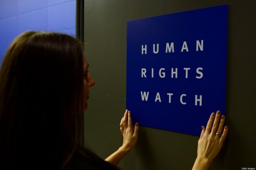 A woman puts a logo of US-based rights group Human Rights Watch on the door as she prepares the room before their press conference to release their annual World report on January 21, 2014 in Berlin [JOHN MACDOUGALL/AFP via Getty Images]