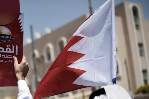 Bahraini men hold up a national flag [MOHAMMED AL-SHAIKH/AFP via Getty Images]