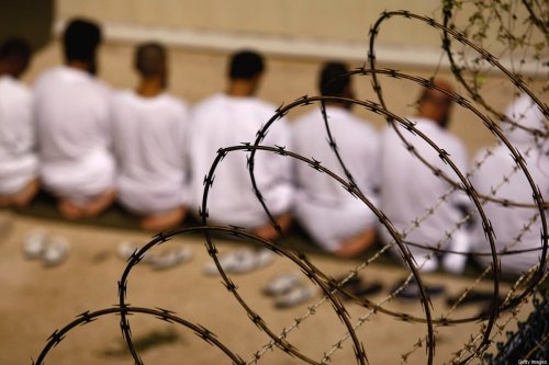 A group of detainees kneel during an early morning Islamic prayer in their camp at the US military prison for "enemy combatants" on October 28, 2009 in Guantanamo Bay, Cuba [John Moore/Getty Images]