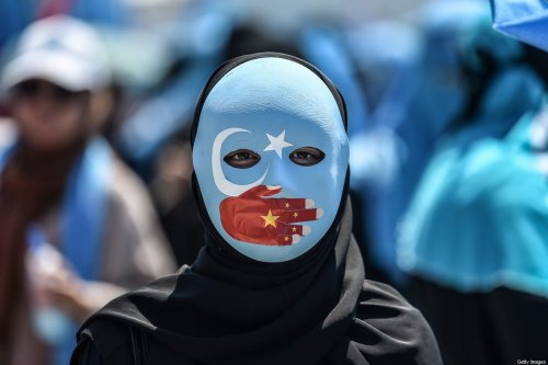 A demonstrator wearing a mask painted with the colours of the flag of East Turkestan and a hand bearing the colours of the Chinese flag attends a protest of supporters of the mostly Muslim Uighur minority and Turkish nationalists to denounce China's treatment of ethnic Uighur Muslims during a deadly riot in July 2009 in Urumqi, in front of the Chinese consulate in Istanbul, on July 5, 2018 [OZAN KOSE/AFP via Getty Images]